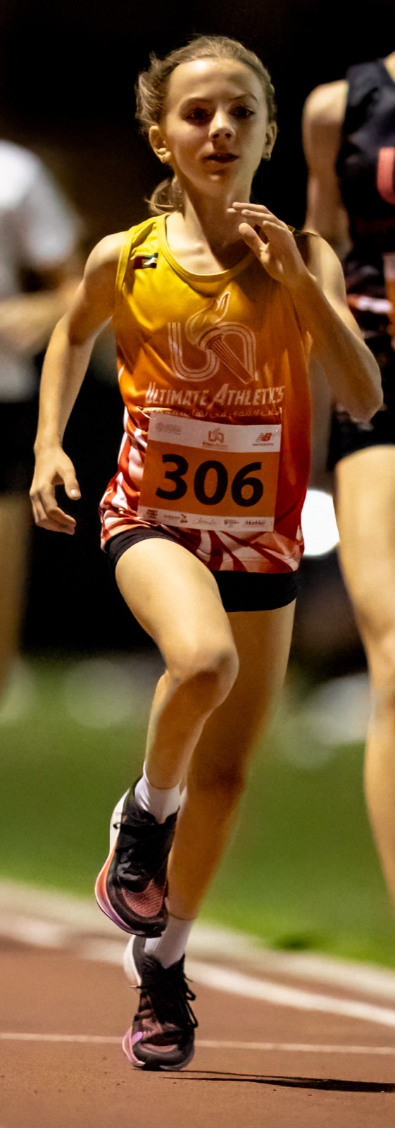 Carla running at night on a track, bib 306