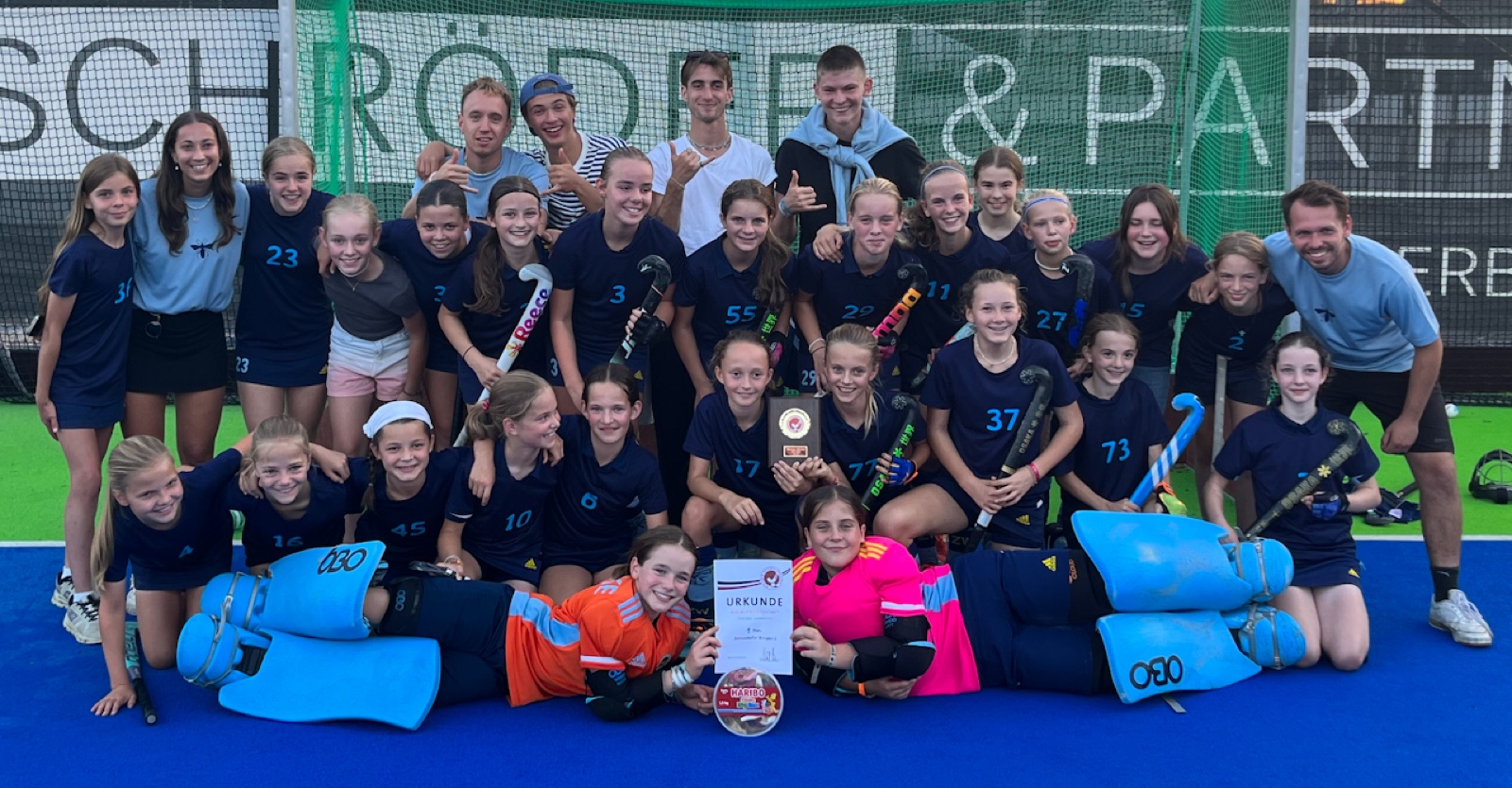 Zehlendorfer Wespen girls' team on a blue pitch holding a certificate