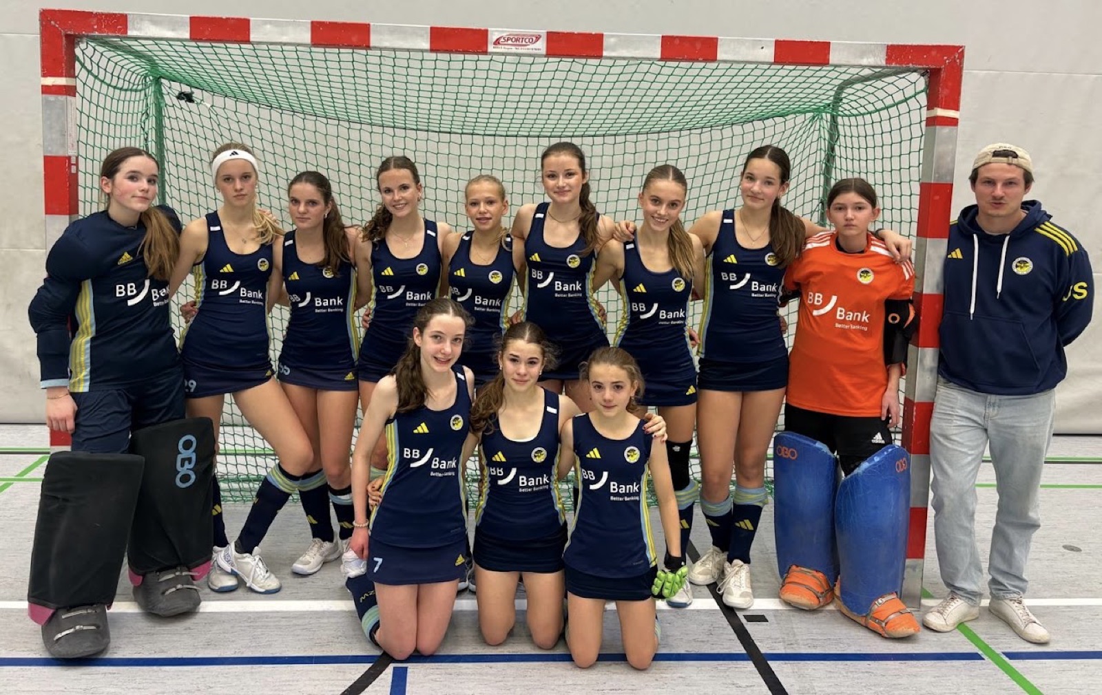 Zehlendorfer Wespen girls' team in dark blue kits in front of an indoor goal