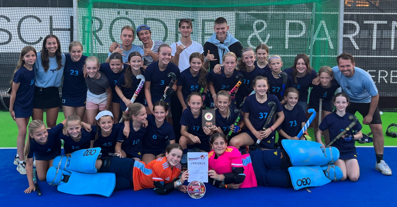 Zehlendorfer Wespen girls' team on a blue pitch holding a certificate