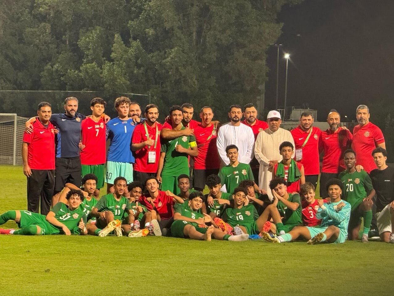 Shabab Al Ahli youth team photo at night with coaches and staff